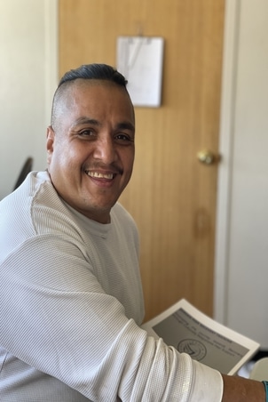 male in white shirt smiling with dark hair
