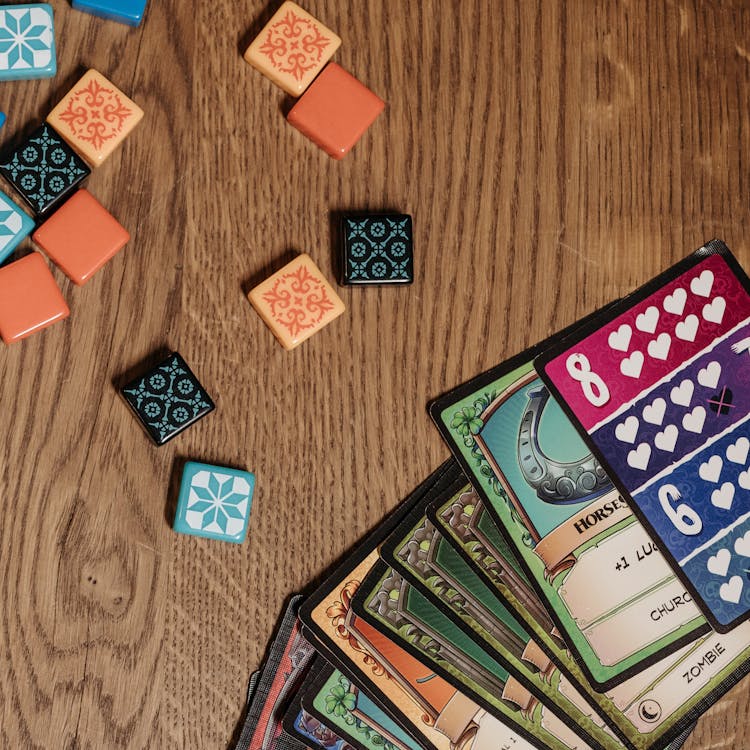 A variety of board game cards and tiles laid out on a wooden table, showcasing a fun and strategic gaming setup.